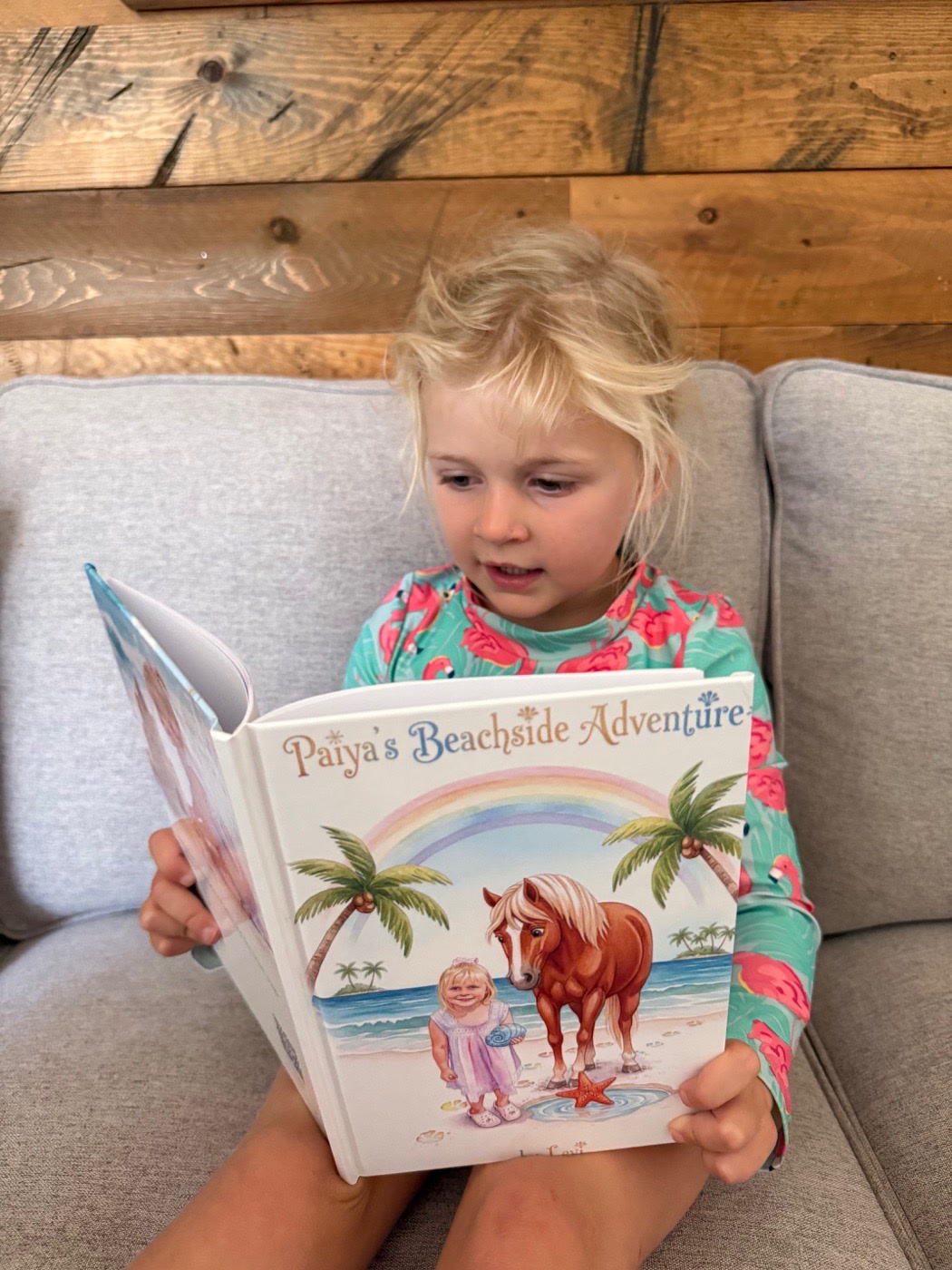 Paiya reading her personalized horse storybook on a couch